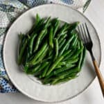 Plate of green beans with mustard sauce and a fork.