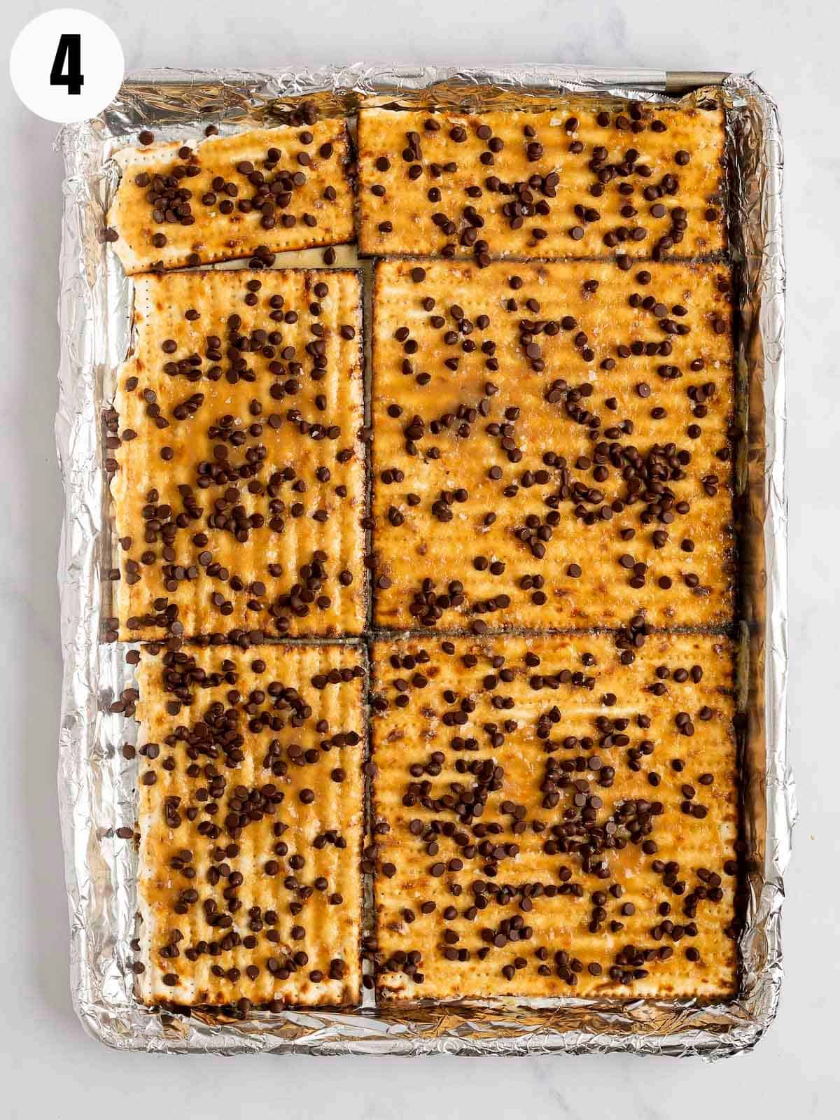 Matzo on a baking sheet with toffee and chocolate chips.