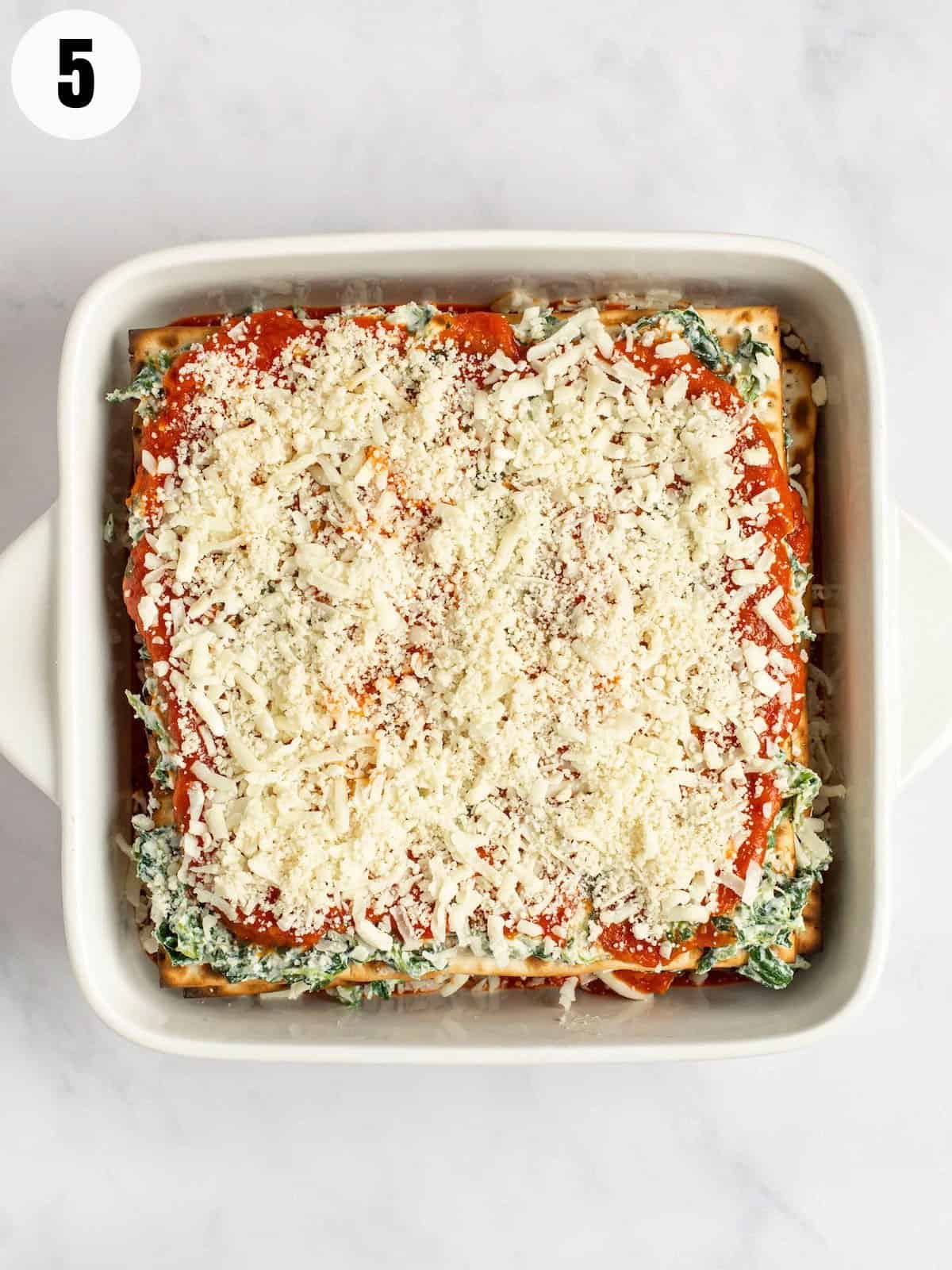 Mozzarella layered on marinara sauce and spinach making lasagna.