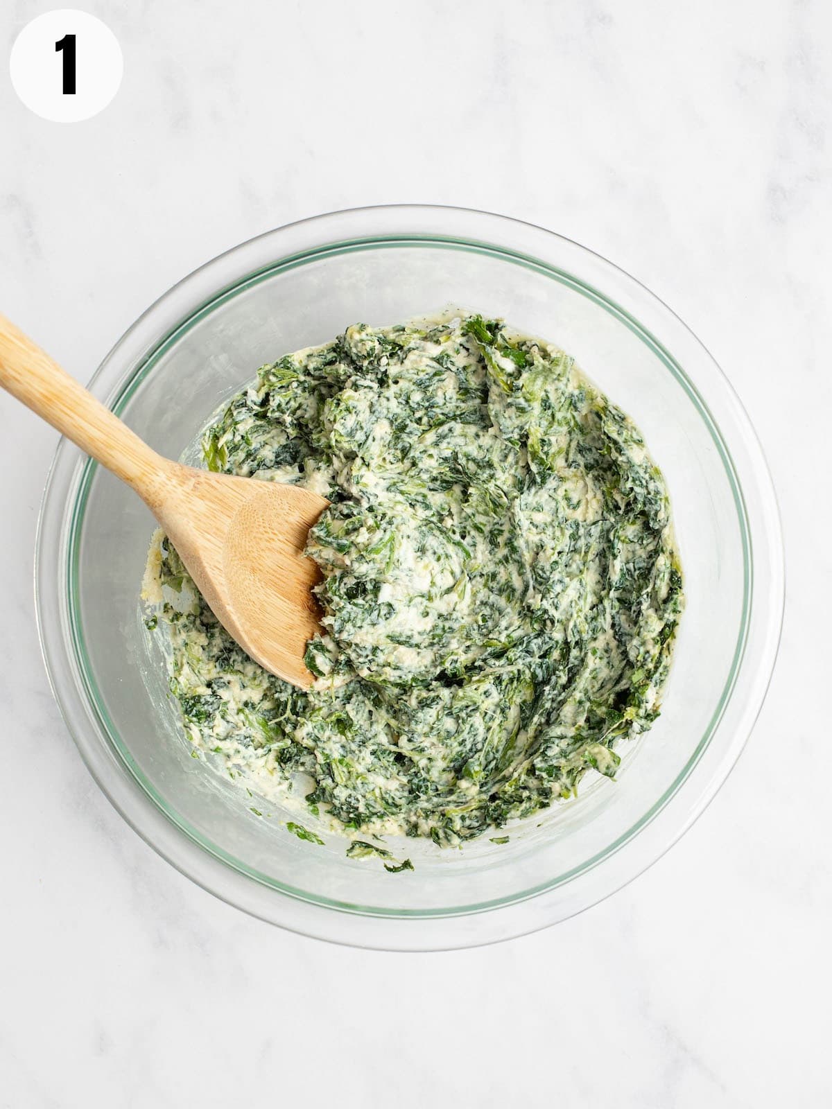 A mixing bowl with ricotta and spinach.
