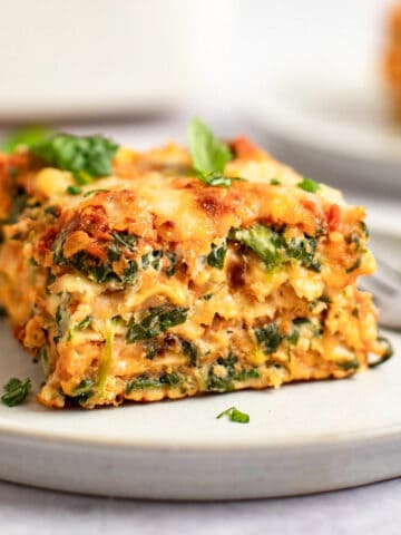 A slice of matzo spinach lasagna topped with fresh basil on a plate.