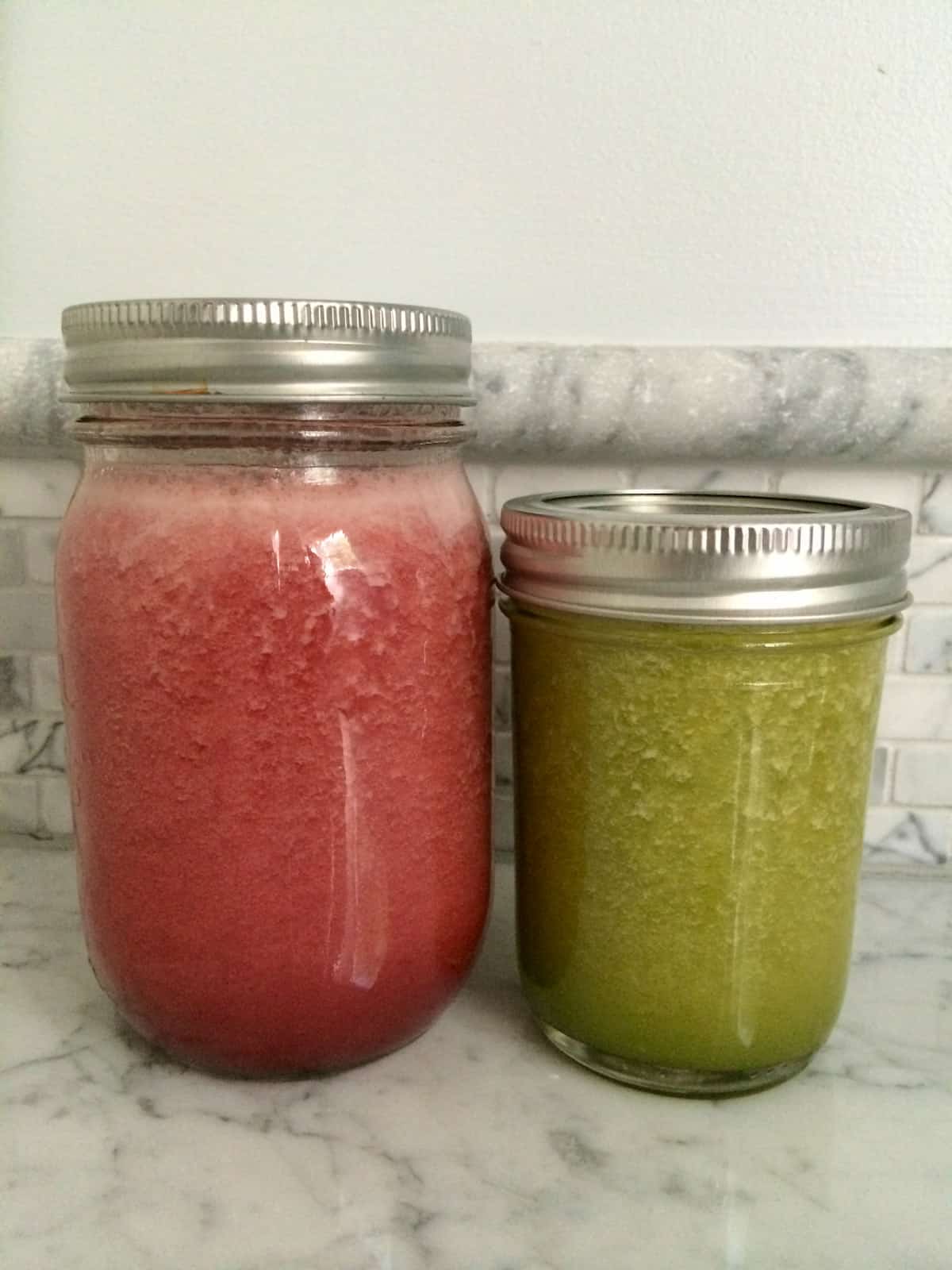 Two glass jars of juice, one red and one green.