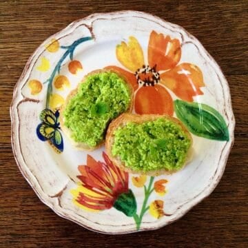 Two crostinis topped with lemon and mint pea puree and placed on floral plate.