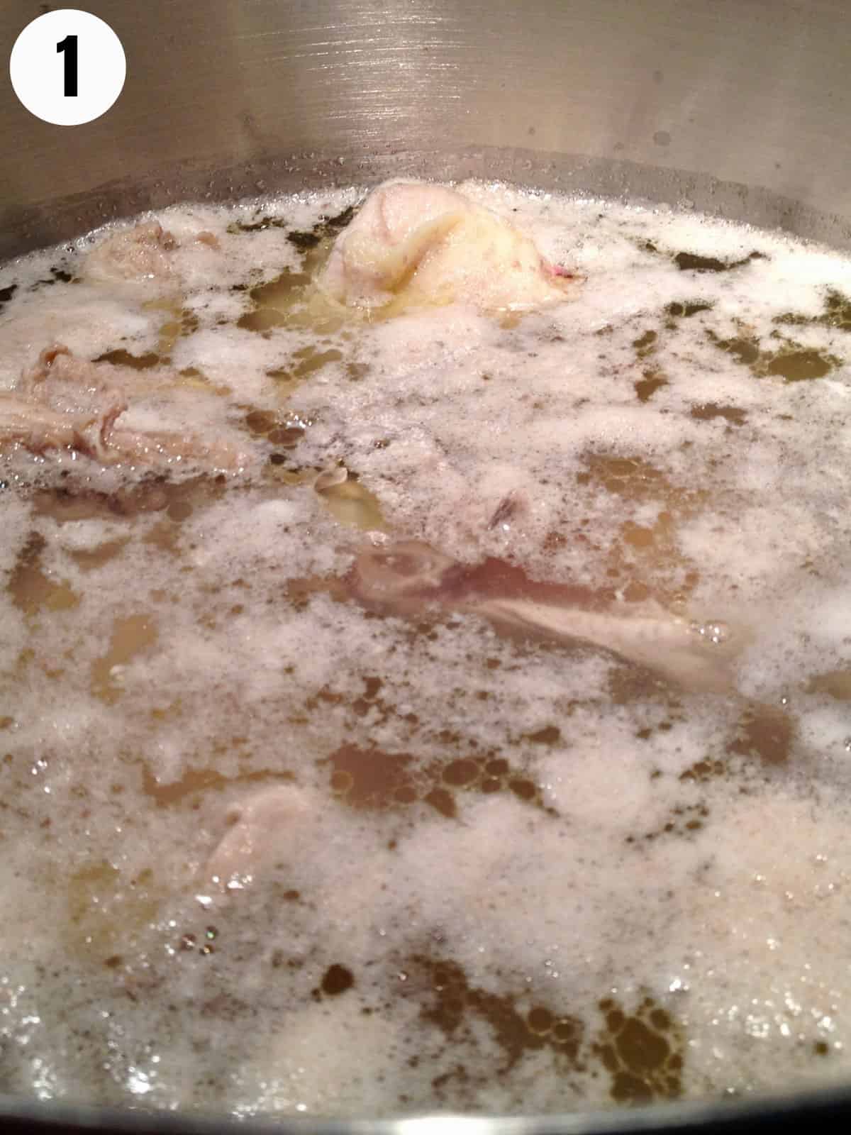 Foam rising to the top of simmering chicken broth.