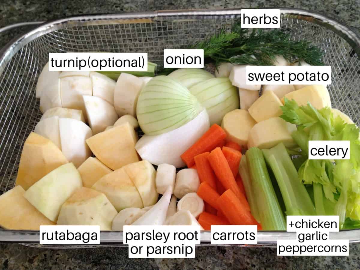 Vegetables to make chicken broth in a colander.