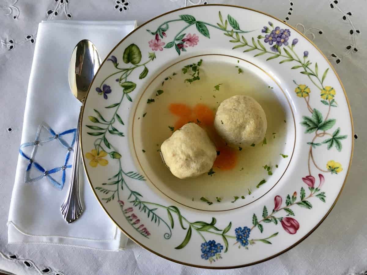 Chicken matzo ball soup in a bowl with a spoon.