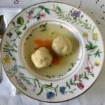 Chicken matzo ball soup in a bowl with a spoon.