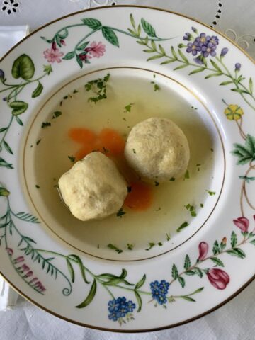 Chicken matzo ball soup in a bowl with a spoon.