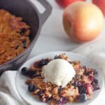 Apple Blueberry Crisp on a plate with a scoop of vanilla ice cream.