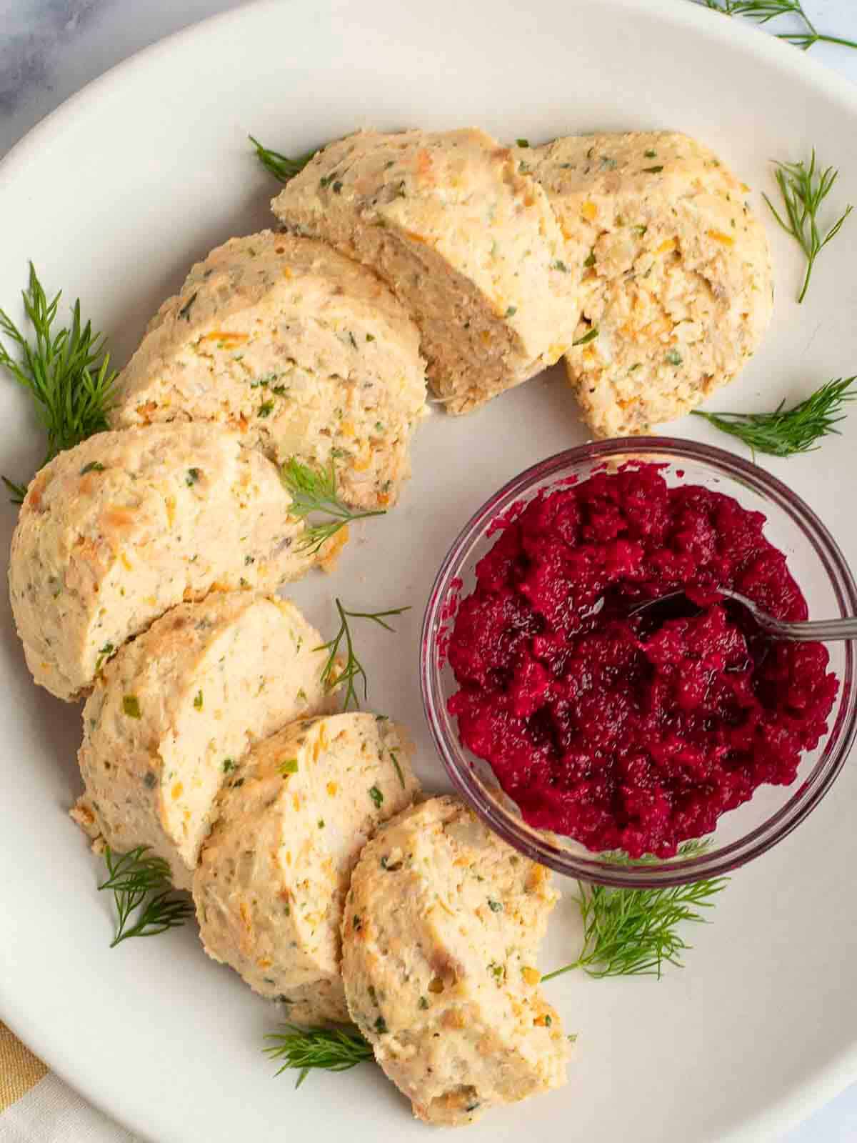 gefilte fish on a platter with horseradish garnished with fresh dill