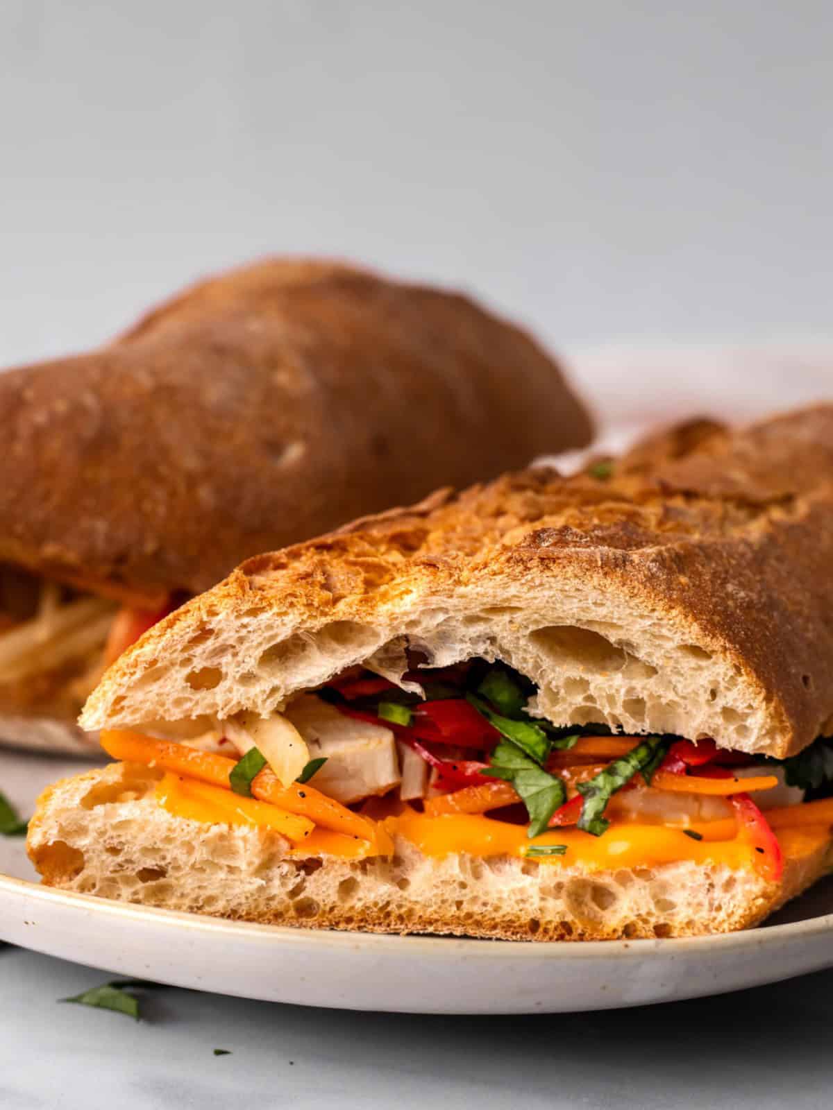 Chicken banh mi sandwich with pickled vegetables on a plate.