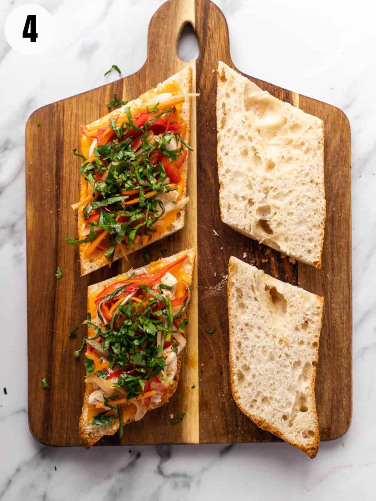 Adding pickled vegetables and cilantro to banh mi sandwich.