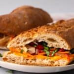 Banh mi chicken sandwich with julienned vegetables on a plate.
