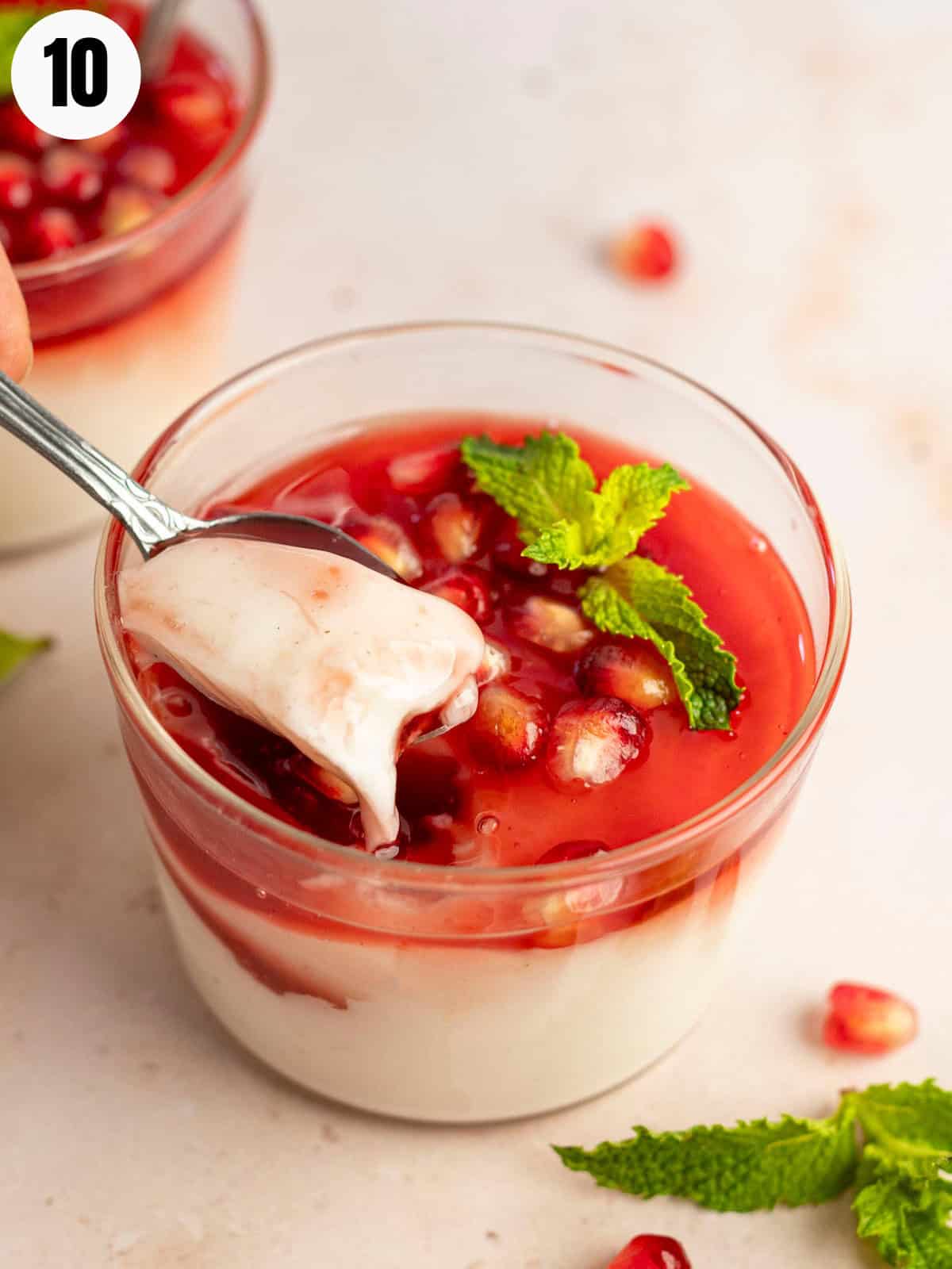 A spoon showing the malabi pudding in a glass bowl.