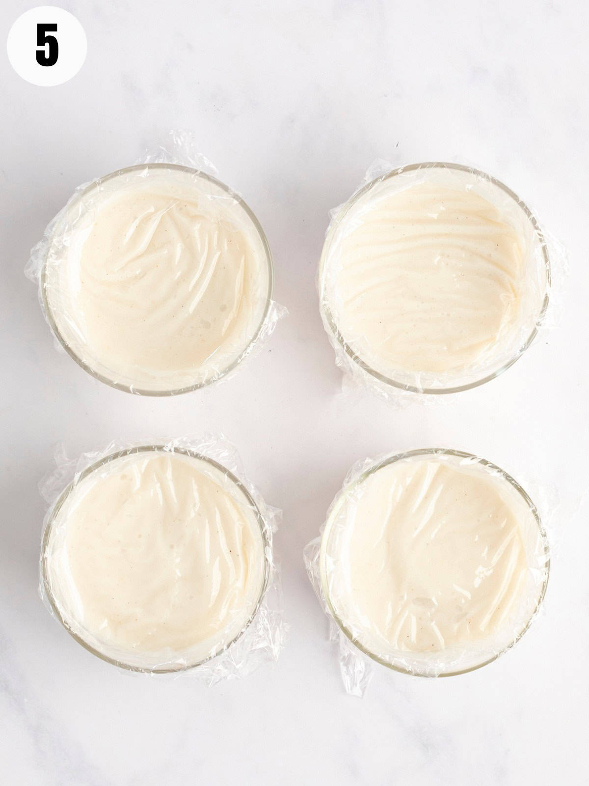 Covering bowls of pudding with plastic wrap. 
