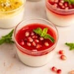 Bowls of malabi pudding with raspberry and peach jam toppings and garnishes.
