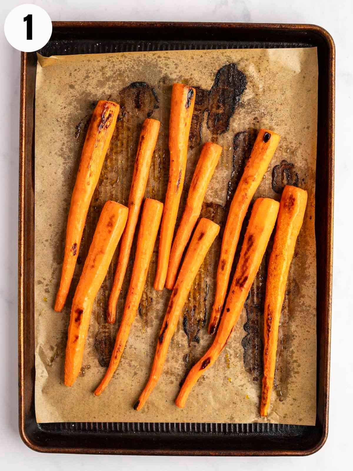Roasted carrots on a parchment lined cookie sheet.