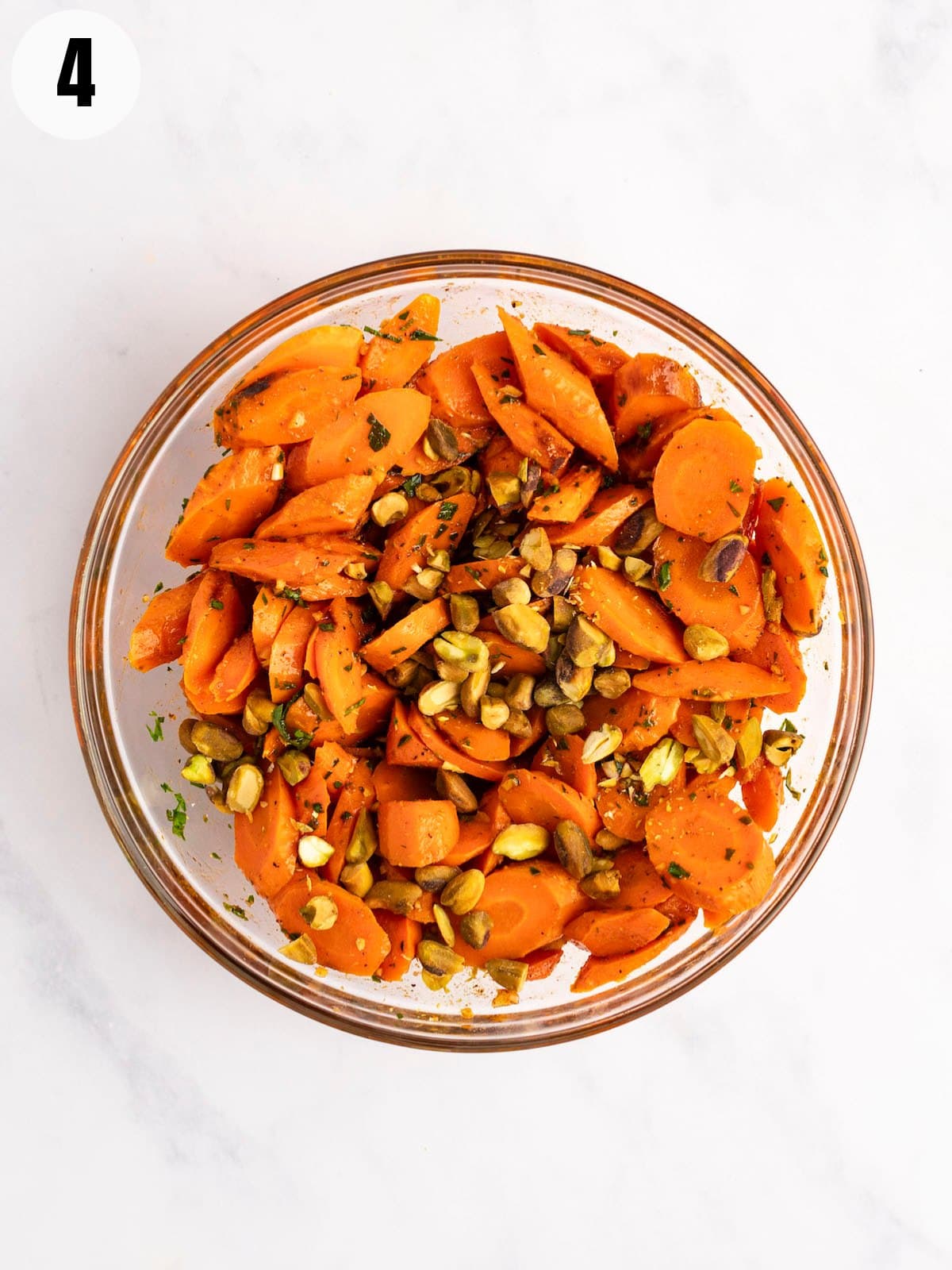 Combining carrots and dressing in a glass bowl.