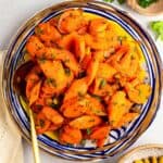 Moroccan carrot salad with parsley garnish in a ceramic serving bowl.