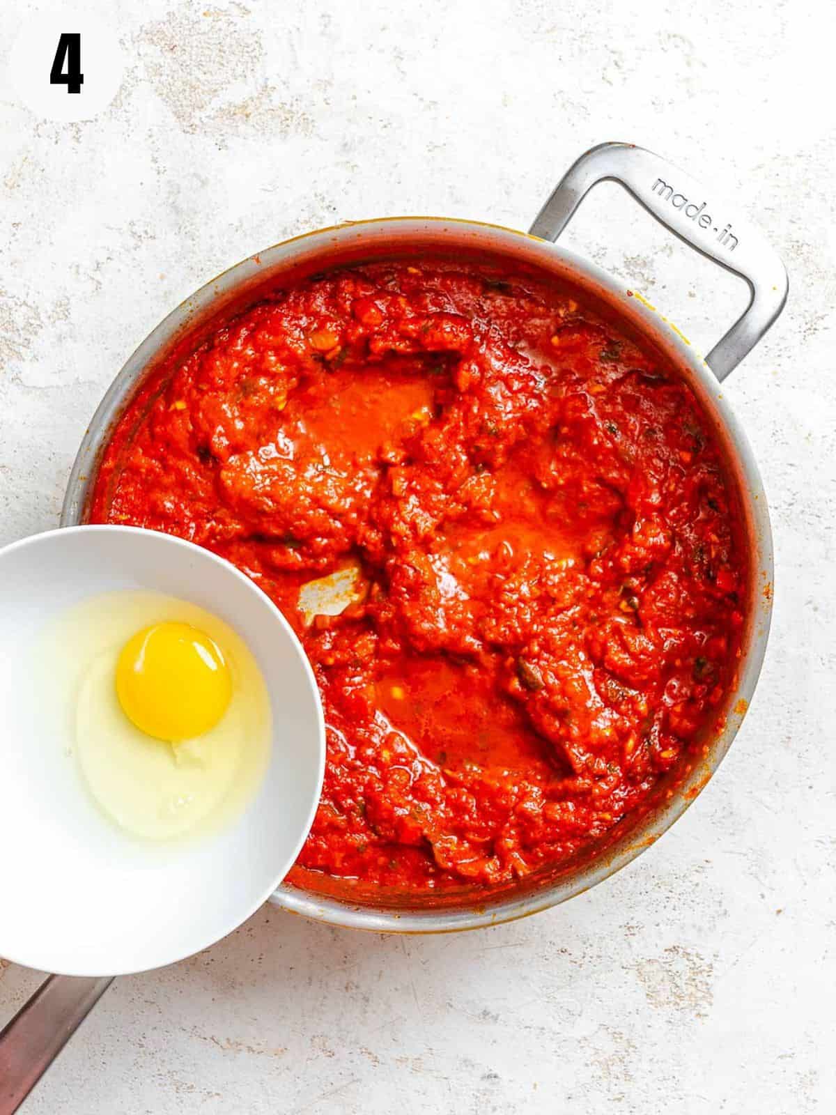 Adding eggs to the pot with the tomato sauce.