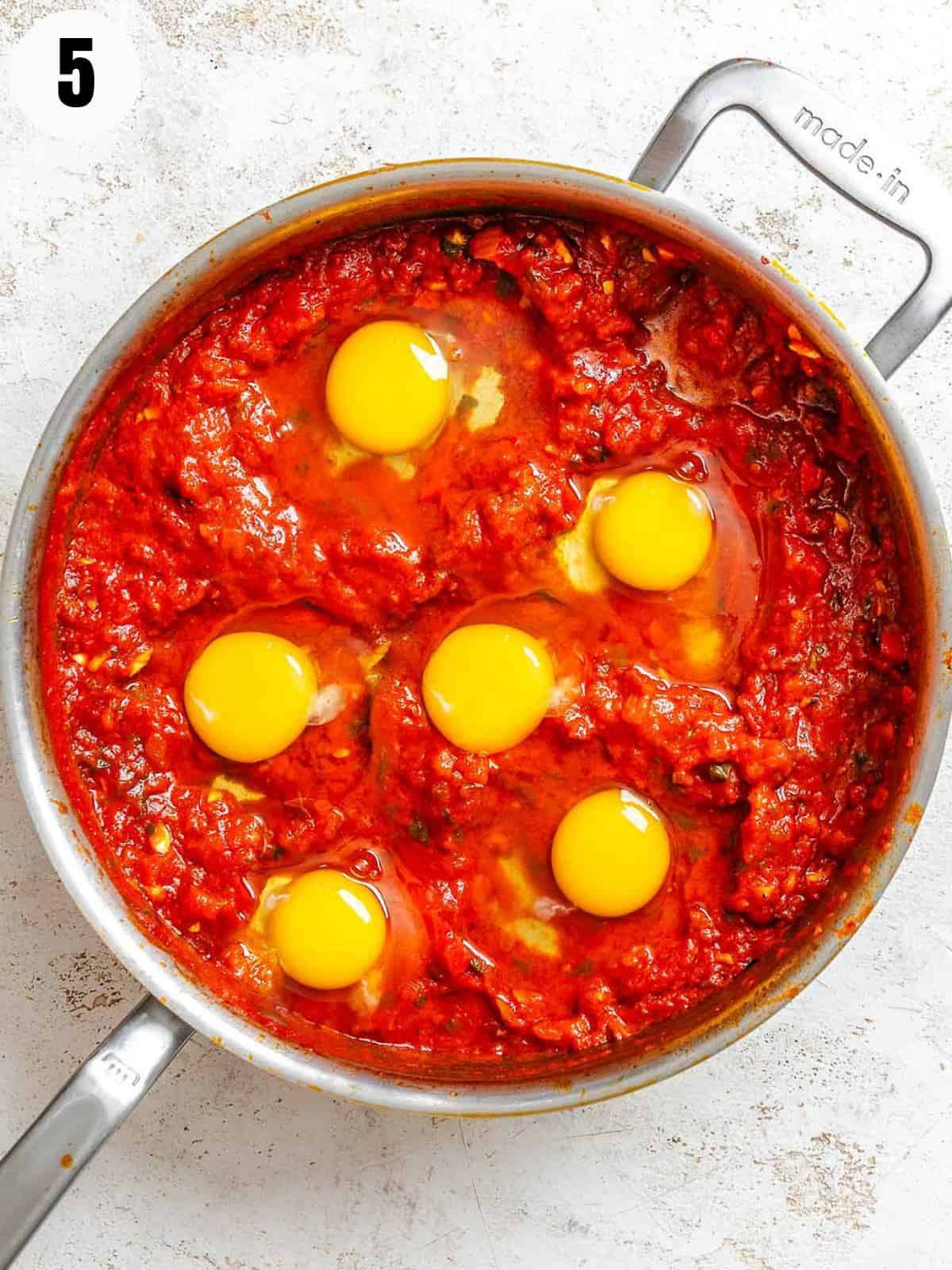 Cooking the eggs in the tomato sauce.