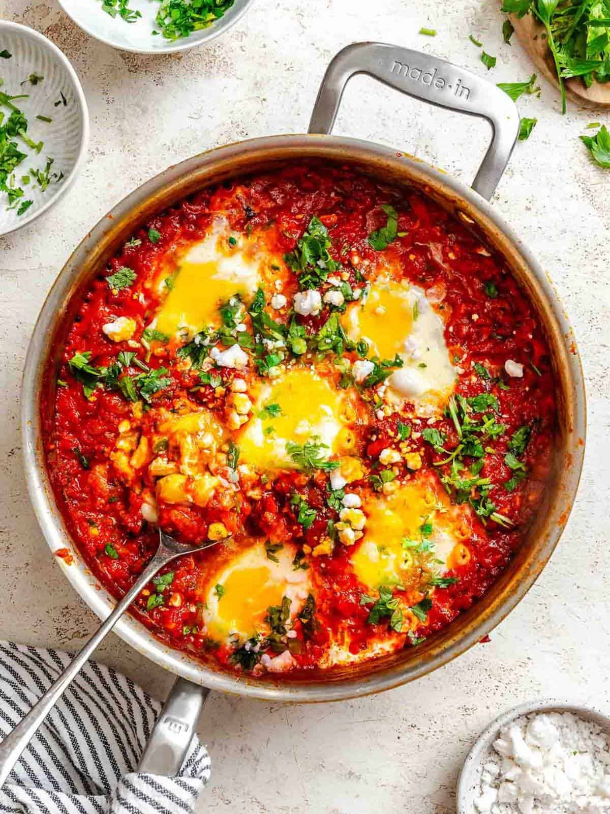Shakshuka garnished with fresh herbs in a pot.