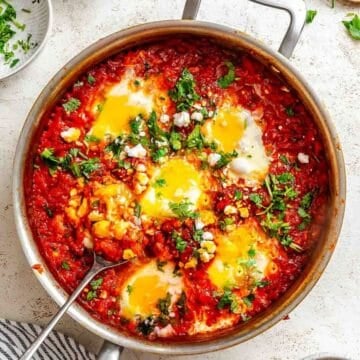 Shakshuka garnished with fresh herbs in a pot.