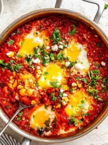 Shakshuka garnished with fresh herbs in a pot.