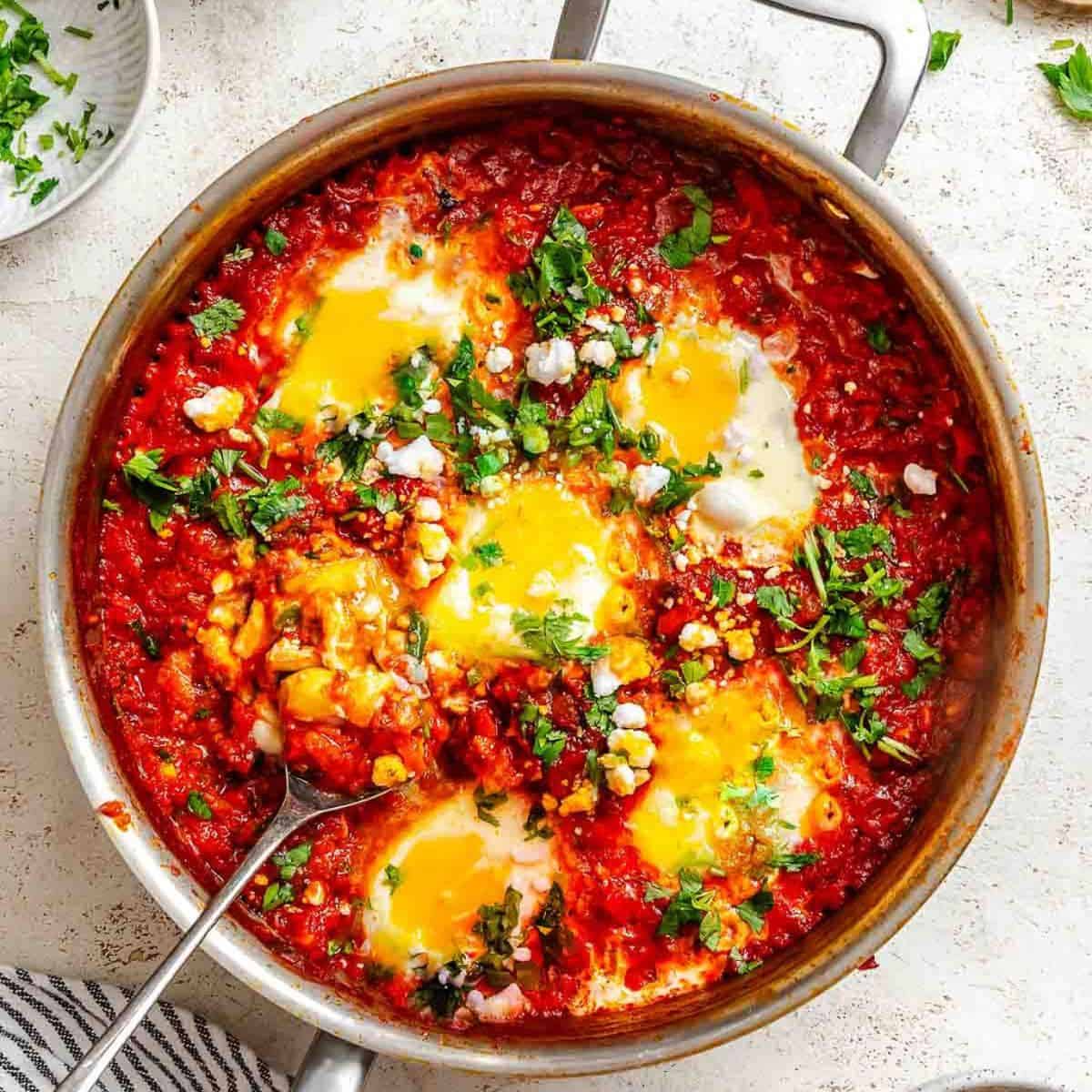 Shakshuka garnished with fresh herbs in a pot.
