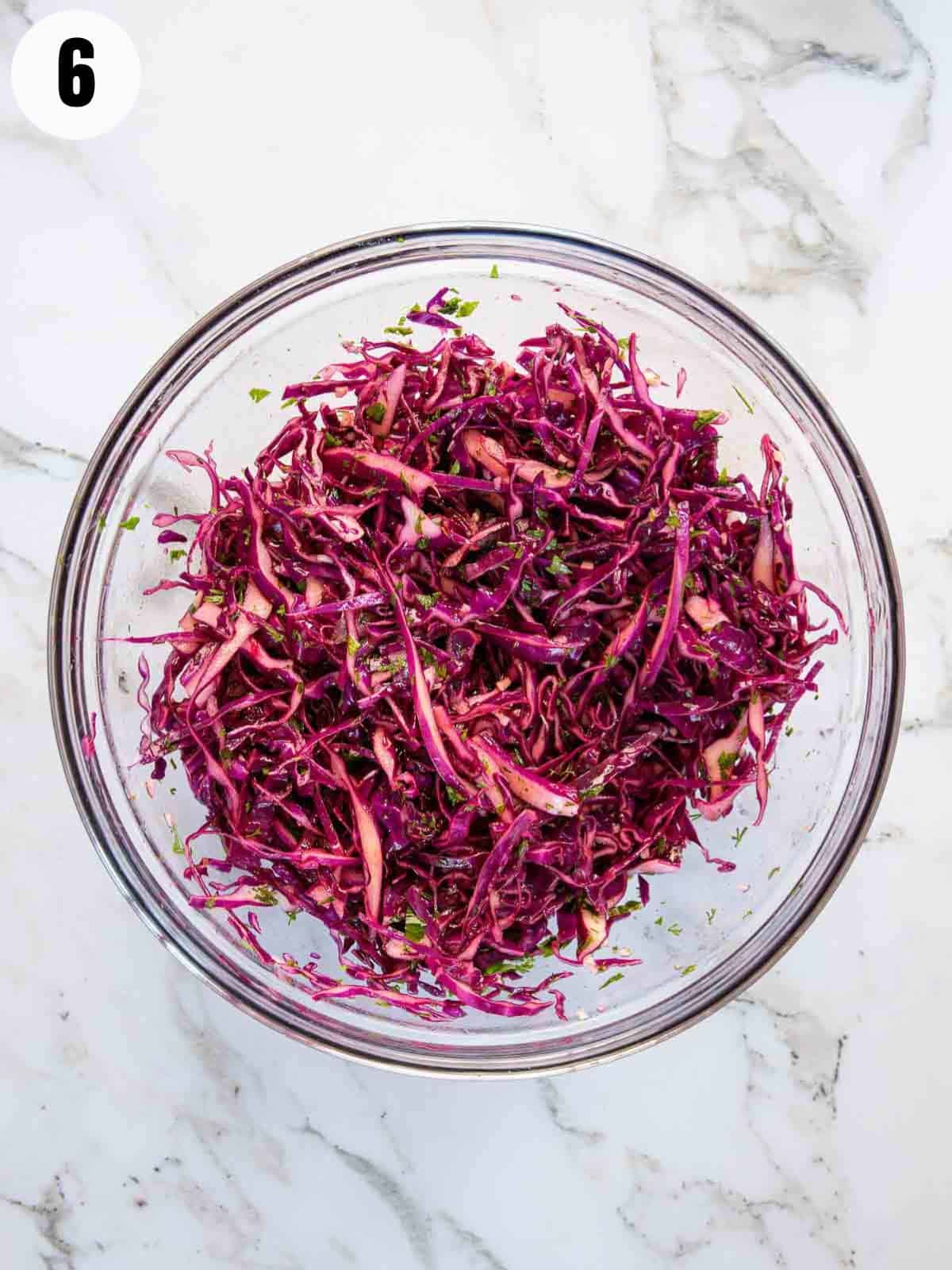 Mixing the sliced cabbage with the dressing.