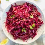 Red cabbage coleslaw in a white bowl.