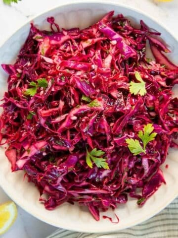 Red cabbage coleslaw in a white bowl.
