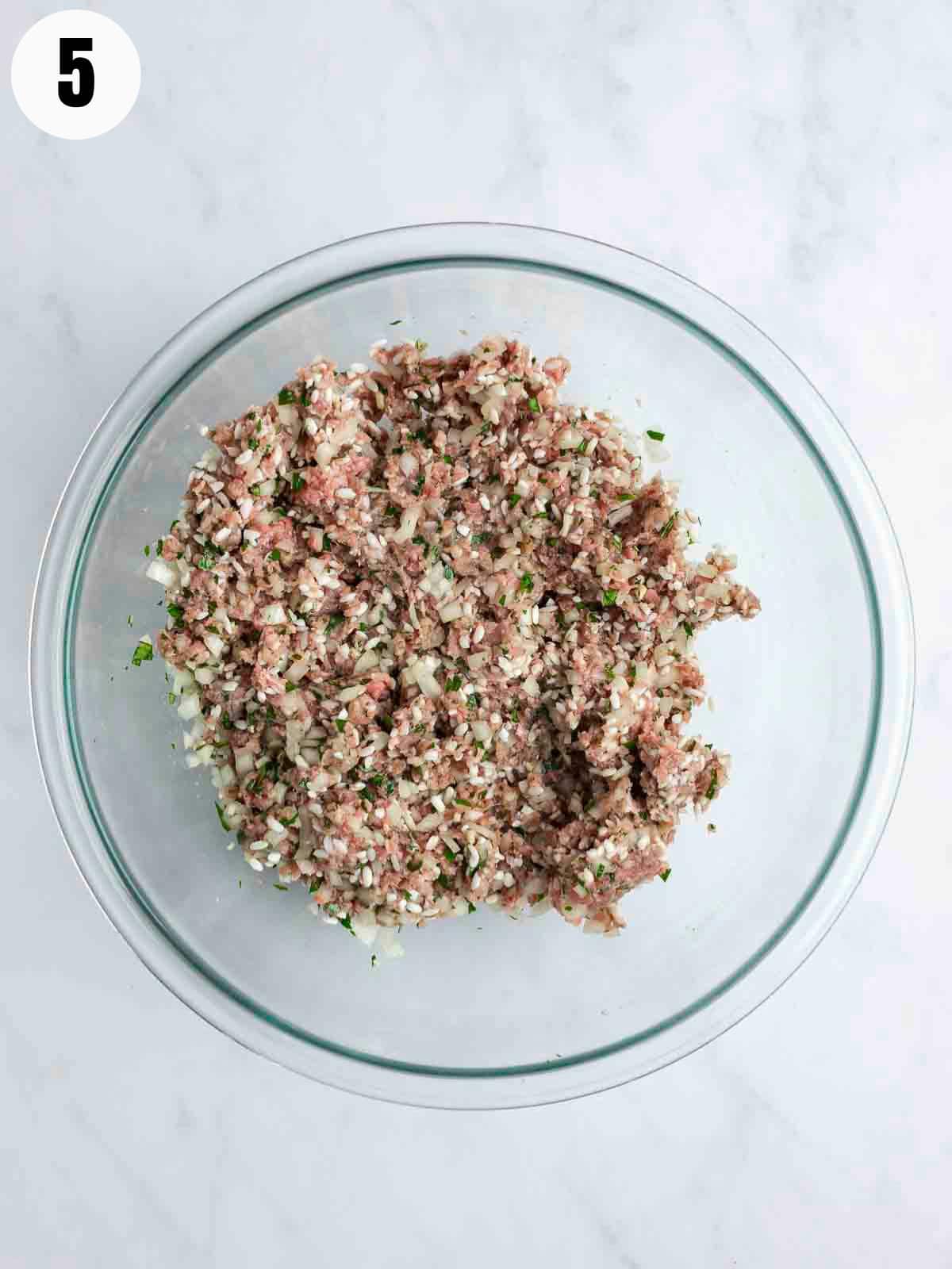 Mixing the ingredients for the meat filling in a glass bowl.