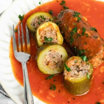 Cut up stuffed zucchini in tomato sauce on a plate.
