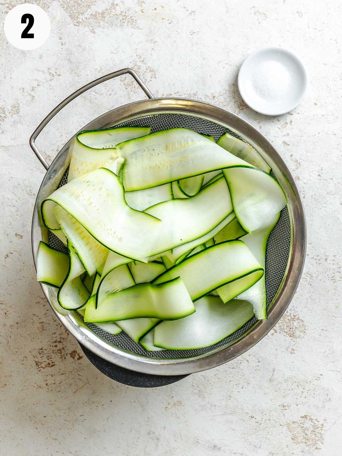 Zucchini ribbons draining in a colander.