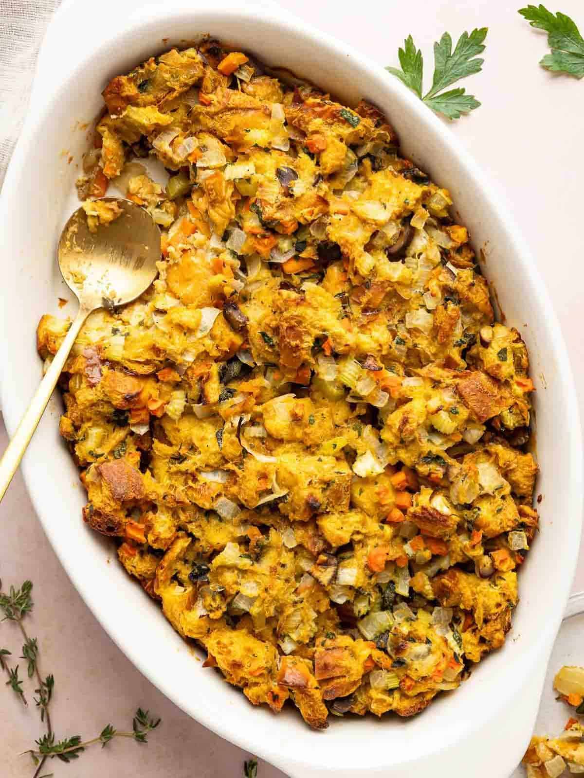 Challah chestnut stuffing in a white serving dish with a spoon.