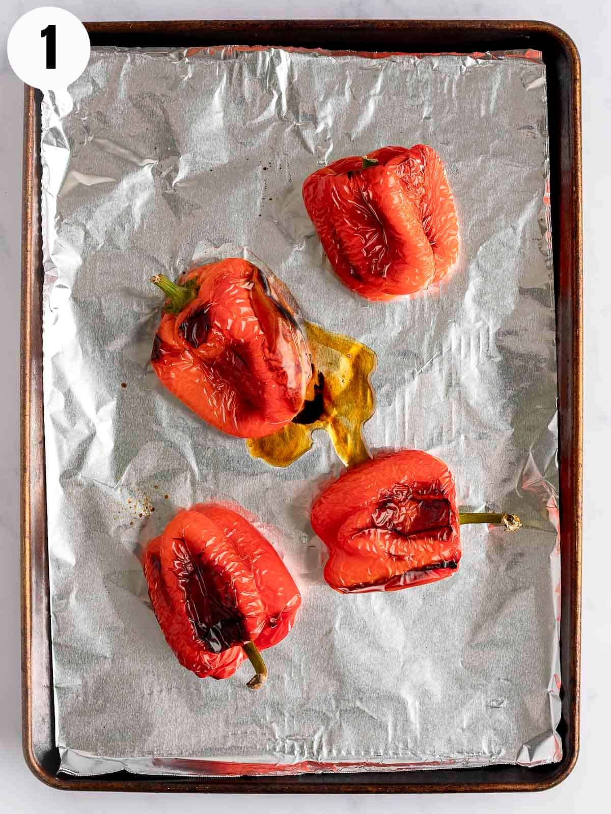 Roasted red peppers on a lined baking sheet.