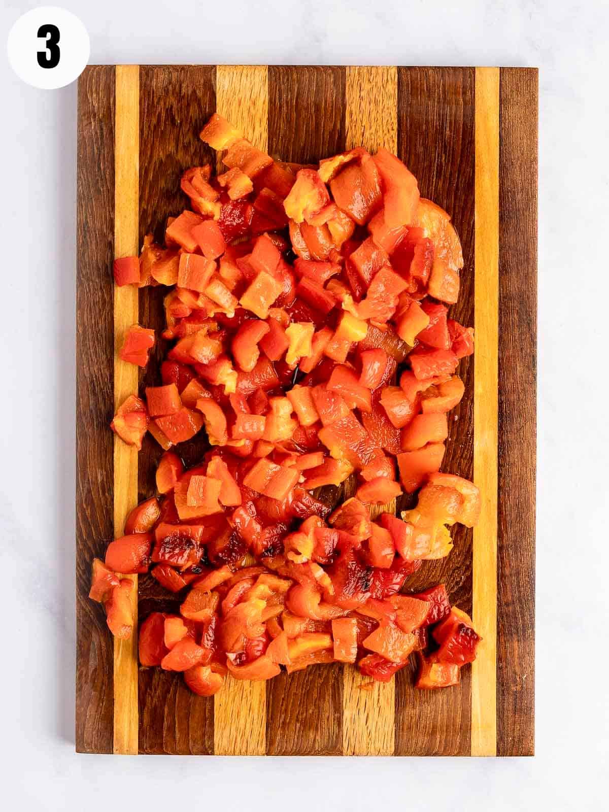 Chopped, roasted, and peeled red peppers on a cutting board.