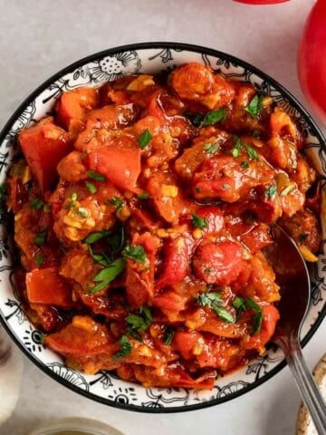Matbucha in a bowl with a spoon.