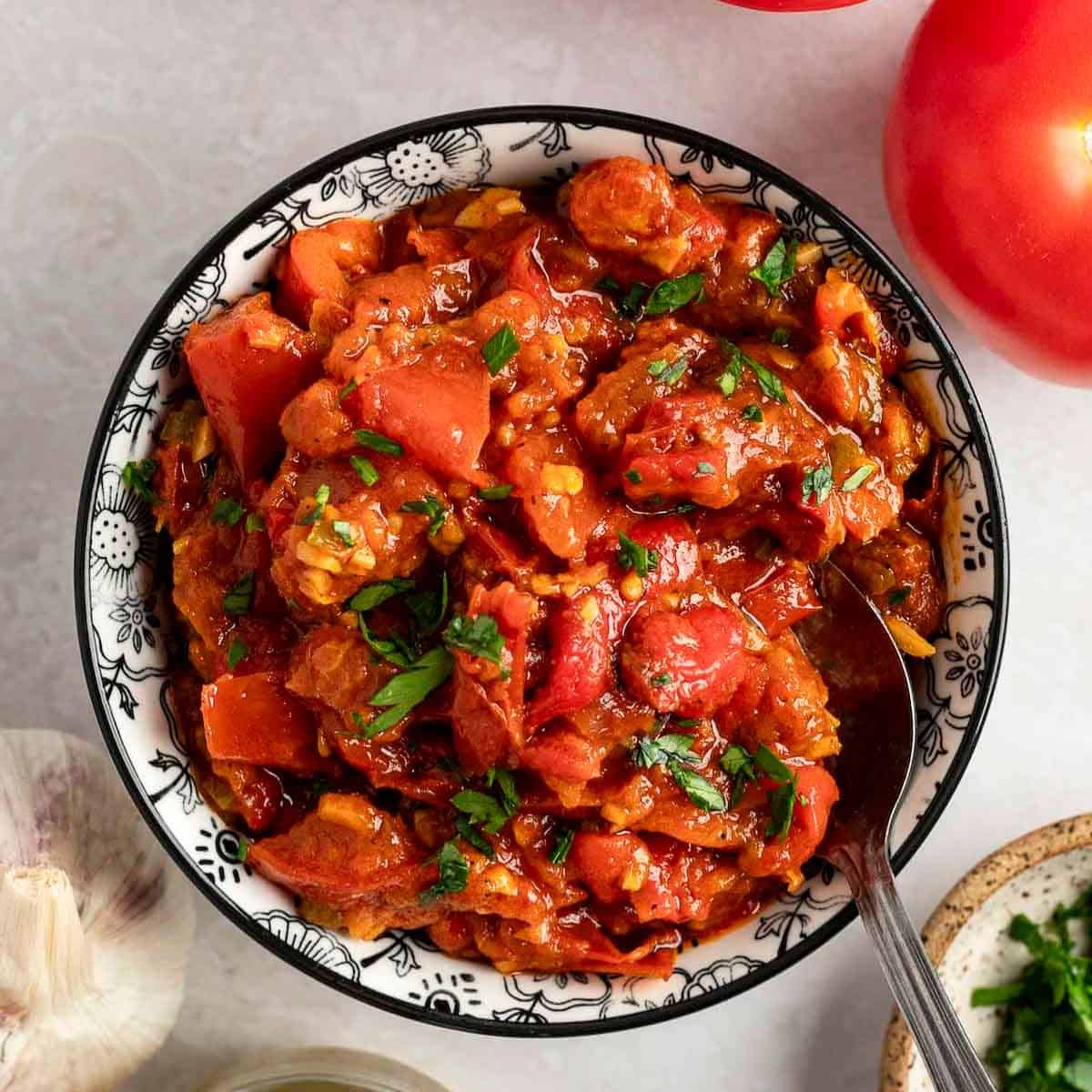 Matbucha in a bowl with a spoon.