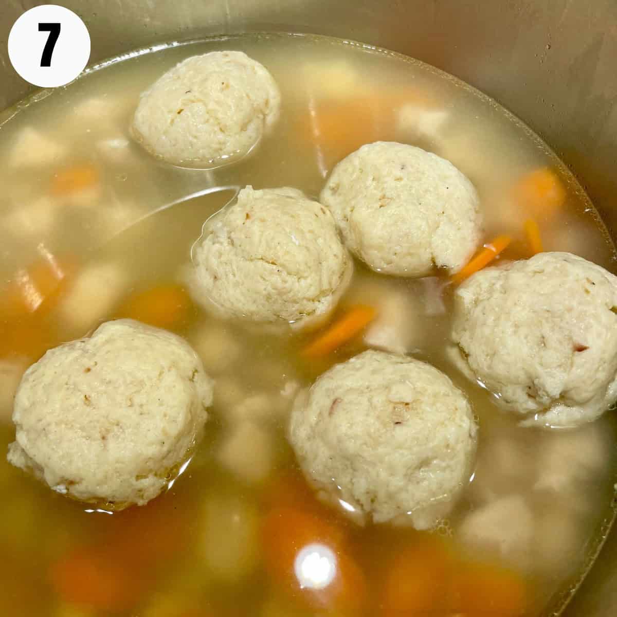 Matzo ball soup heating in soup pot.